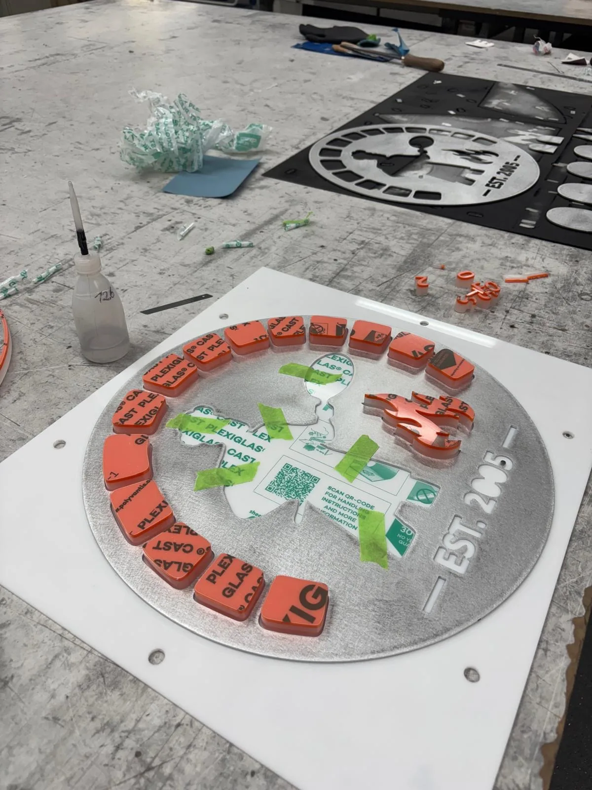 Orangefarbene Acrylelemente für das runde ALTE-FORNO-Signet auf einer Werkbank